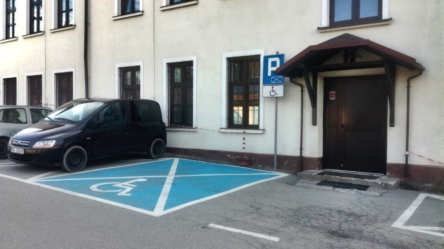 Na zdjęciu widoczne tylne wejście do budynku nr 82 przy ulicy Zdrojowej 82 oraz miejsce parkingowe dla osoby niepełnosprawnej
